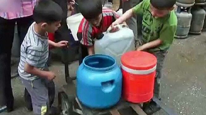 Niños recogen agua en Alepo