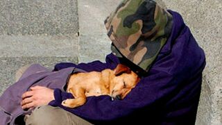 Un persona sin techo cobija a su perro