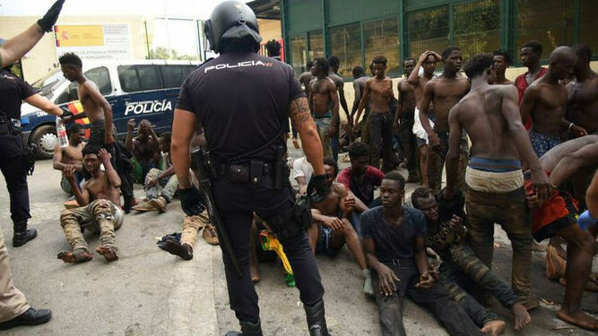 Migrantes y policías en la valla de Ceuta