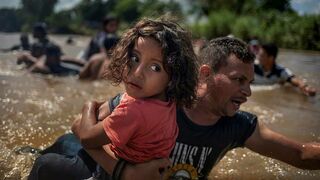 Un inmigrante hondureño Luis Acosta lleva a su hijo a través del río Suchiate