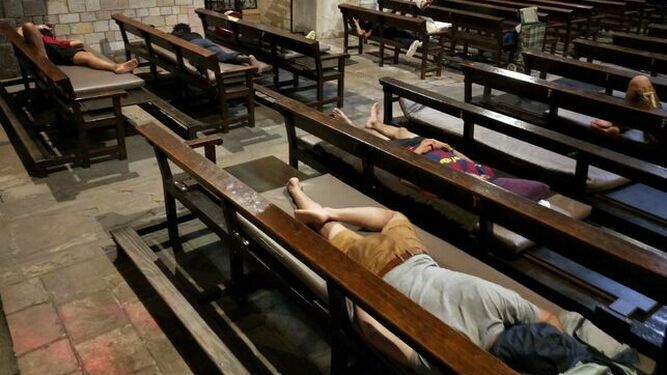 Varios jóvenes migrantes, algunos de ellos menores, durmiendo en los bancos de la Iglesia Santa Anna de Barcelona