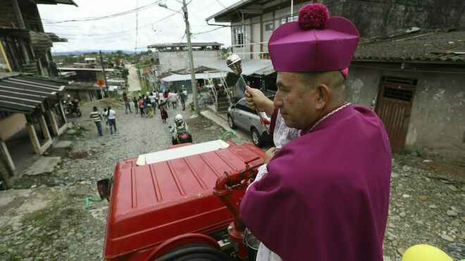 El obispo católico Rubén Darío Jaramillo Montoya rocía agua bendita mientras viaja sobre un camión de bomberos en Buenaventura, Colombia