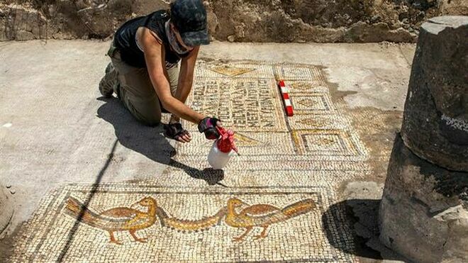 Fotografía facilitada por el Instituto Zinman de Arqueología de la Universidad de Haifa, de la arqueóloga Jessica Rentz limpia el mosaico, en la que se ven las figuras de dos aves y una inscripción en griego