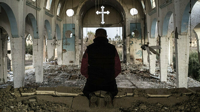 Un hombre reza en una iglesia siria destrozada