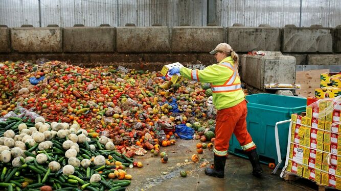 Una trabajadora tira los desperdicios de alimentos antes del consumo