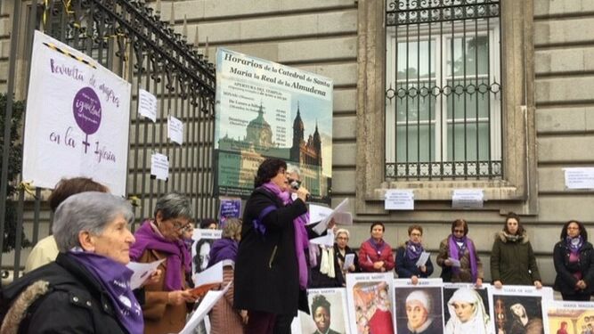 La teóloga Pepa Torres sobre el escenario, rodeada de los carteles de mujeres históricas de Iglesia
