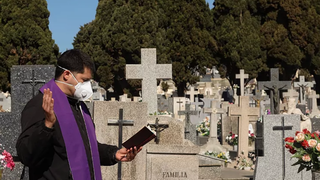 Sacerdote reza un responso en el cementerio