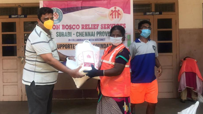 El padre Johnson entrega las bolsas de emergencia a una mujer de los slums. Chennai