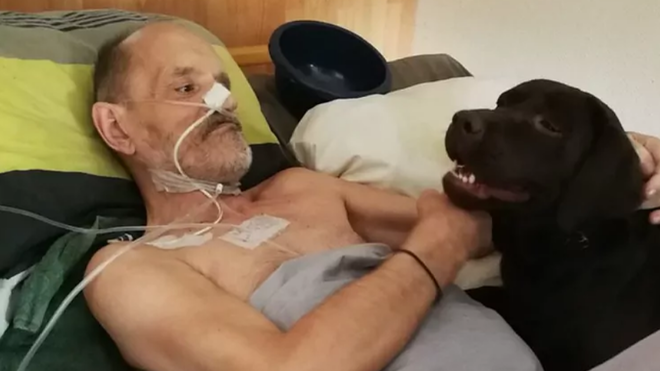 Alain Cocq, postrado en su cama, junto a su perro