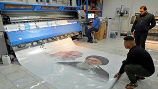 Voluntarios imprimen un cartel con motivo del encuentro entre Francisco y Al Sistani