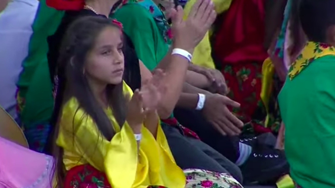 Un niña romaní escucha a Francisco