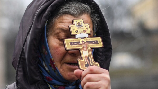 Una mujer se refugia en el crucifijo ortodoxo