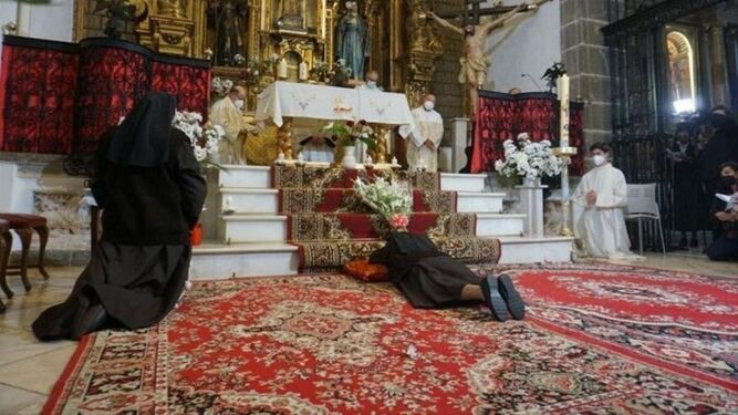 Monjas arrodilladas ante un altar en donde hay tres sacerdotes