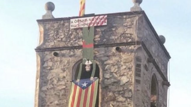 Campanario con una estelada y la figura del rey boca abajo