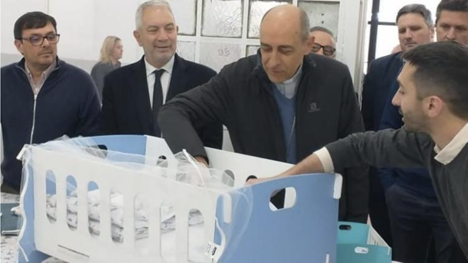 El arzobispo observa una de las cunas que fabrican los internos