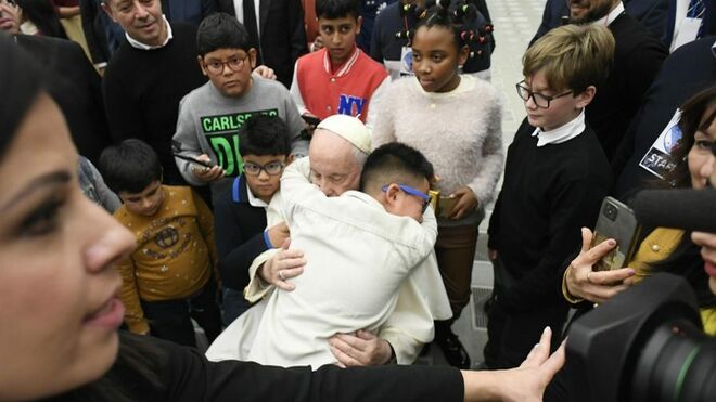 Un niño se abraza al Papa durante su visita al dispensario de Santa Marta