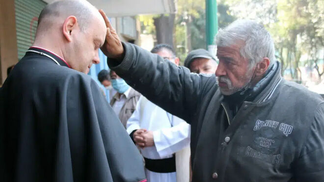 El obispo Francisco Javier Acero recibiendo la bendición de un indigente