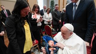 Francisco coge a un bebé en sus brazos