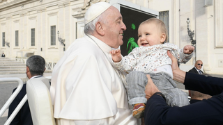 Francisco saluda a un bebé en la plaza de San Pedro