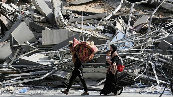 Habitantes de Gaza caminan con sus pertenencias en medio de la destrucción
