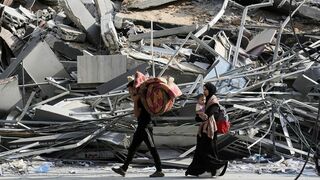 Habitantes de Gaza caminan con sus pertenencias en medio de la destrucción