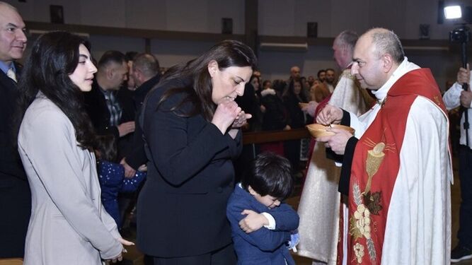 Diyar Sarkis da la comunión a su mujer e hija tras ser ordenado sacerdote en Holanda