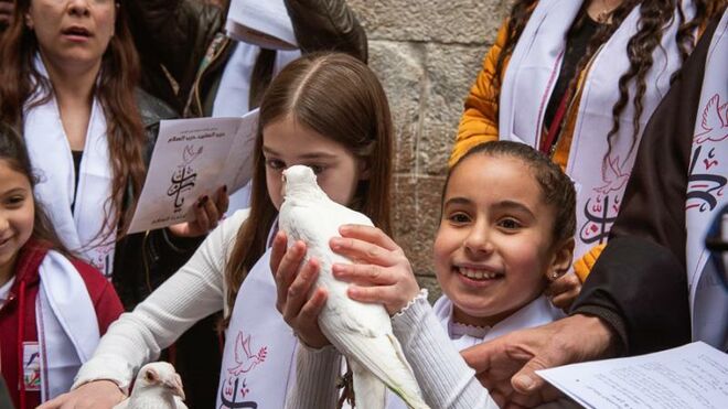 Dos niñas lanzan palomas durante el via crucis por las calles de Jerusalen