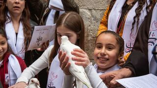 Dos niñas lanzan palomas durante el via crucis por las calles de Jerusalen
