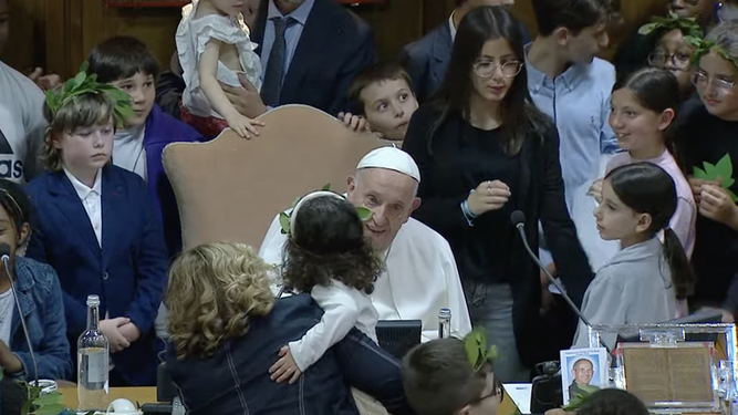 Una niña saluda al papa durante la mesa redonda con niños en el Aula del Sínodo