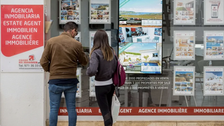 Una pareja ante una agencia inmobiliaria