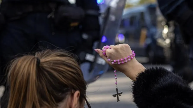 Una mujer con un rosario en las protestas contra el PSOE en la calle Ferraz