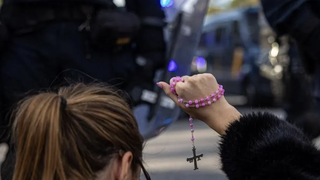 Una mujer con un rosario en las protestas contra el PSOE en la calle Ferraz