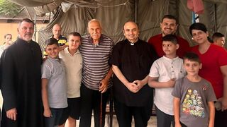 El párroco posa junto a algunos refugiados en el exterior de la iglesia de la Sagrada Familia en Gaza