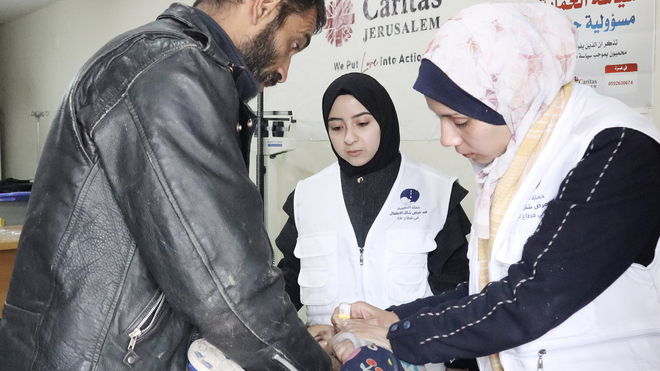 Miembros de Cáritas Jerusalén atienden a un niño en un consultorio