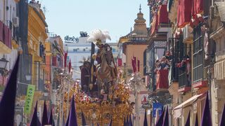 El paso del Cristo de las Tres Caídas, precedido por nazarenos con antifaces morados, en la calle Pureza antes de entrar en la Capilla de los Marineros. - Eduardo Briones - Europa Press