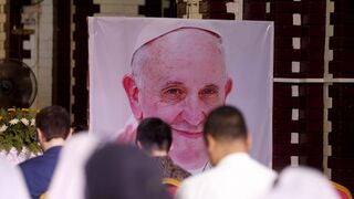 Fieles rezan ante una imagen del Papa