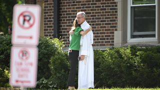 Un sacerdote consuela a una mujer tras el tiroteo en la escuela