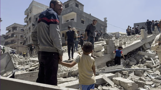 Un hombre y un niño observan los destrozos de un bombardeo en Gaza.