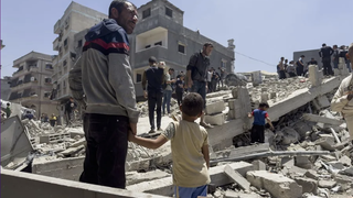 Un hombre y un niño observan los destrozos de un bombardeo en Gaza.