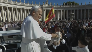 El Papa besa a un niño ante una bandera de España