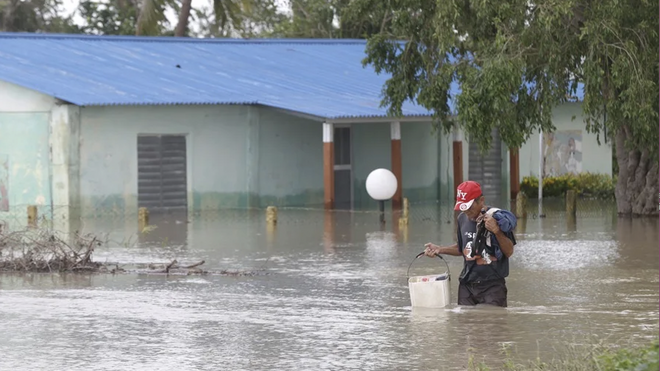 Una persona camina frente a una casa inundada en Cauto Cristo (Cuba)