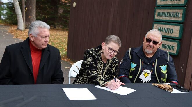 La hermana Sue Ernster firma la venta ante el jefe tribal (derecha)