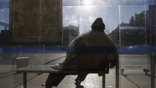 Un sintecho se cobija en una parada de autobús en Madrid