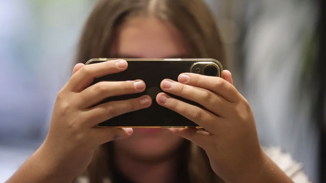 Una adolescente mira su móvil